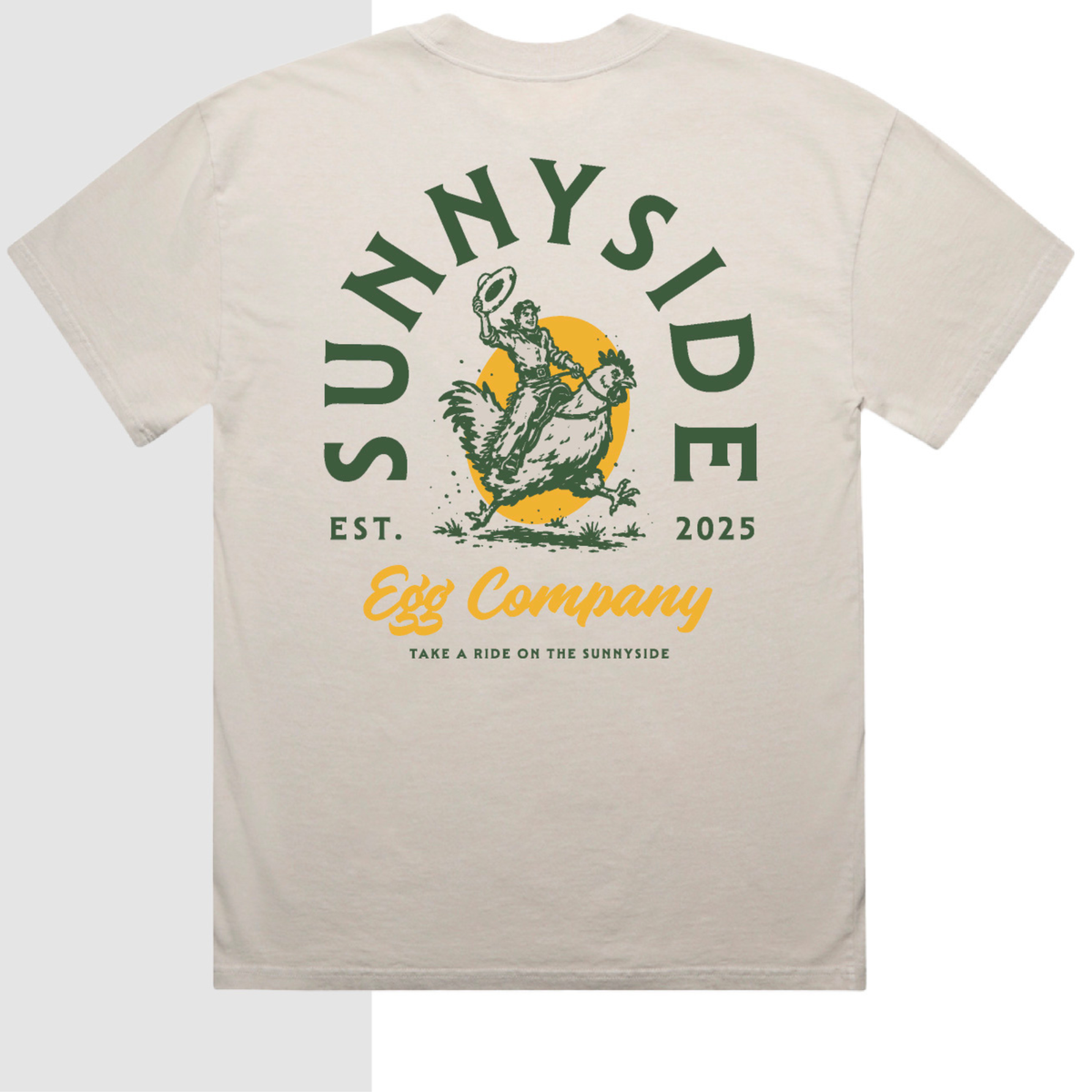 A light beige crewneck t-shirt showing the back graphic, which features a green and yellow design with the text 'SUNNYSIDE', 'EST. 2025', and 'Egg Company'.